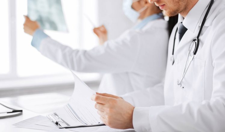 healthcare, medical and radiology concept - two doctors looking at x-ray