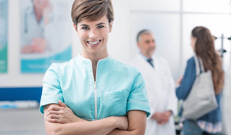 Healthcare professionals at the clinic Smiling young nurse posing at the clinic and holding medical records, a doctor is welcoming a patient on the background